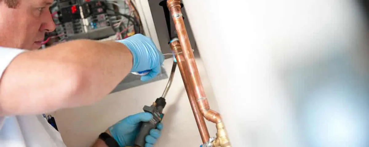 Water heater repair technician testing copper pipe connections and controls in Lynchburg, VA